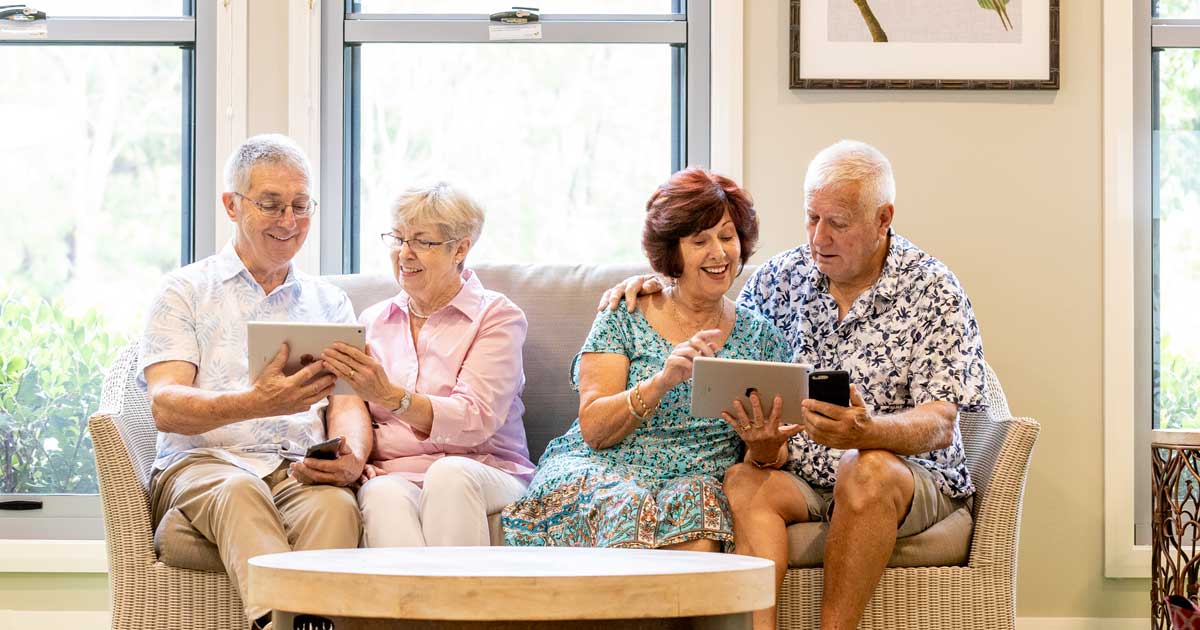 Small group of Elements residents sitting on a couch viewing the Conpago App on their Apple iPads